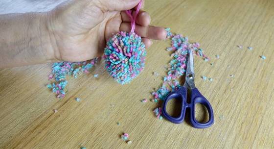 Der Pompon wird mit einer Schere zu einem Ei gestutzt.